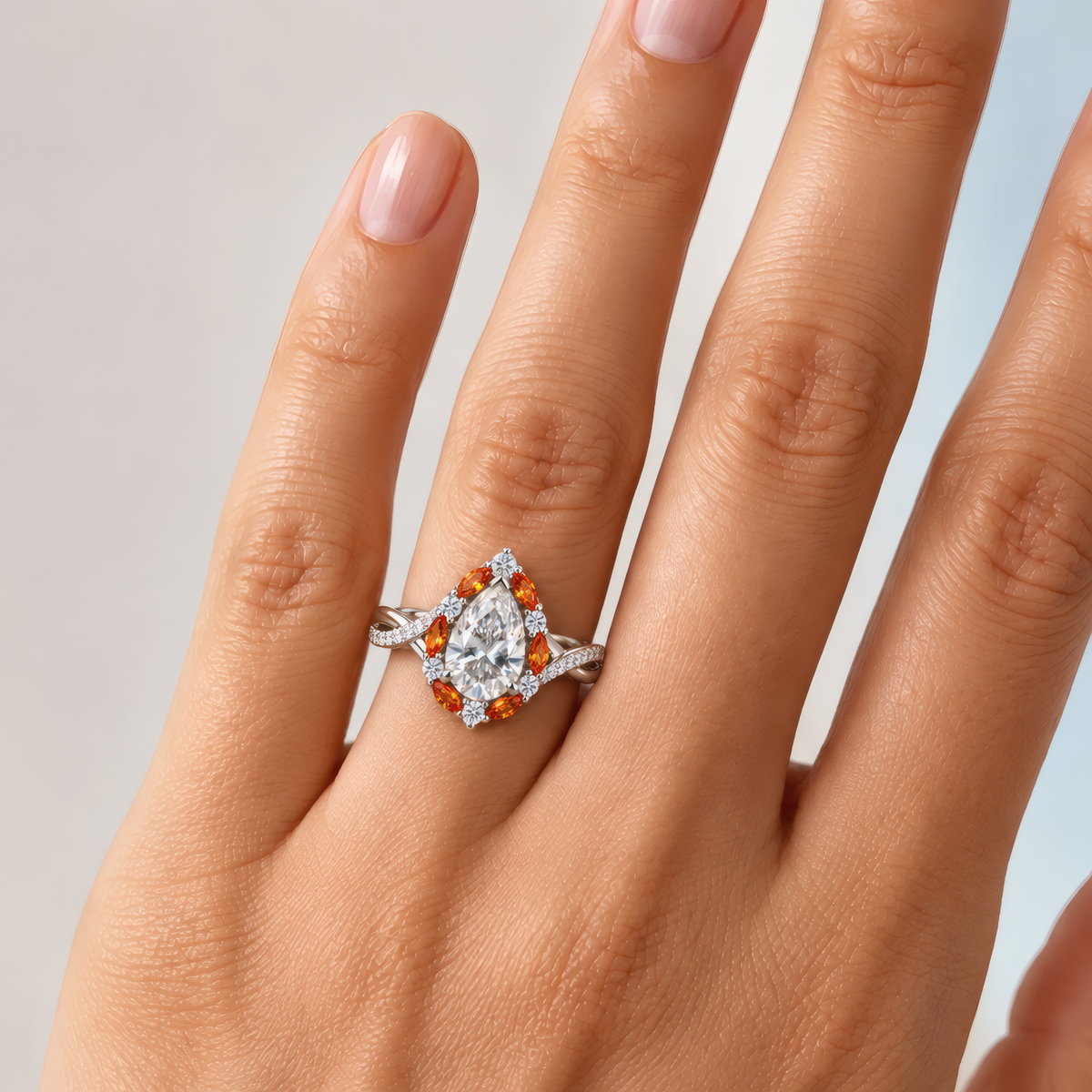 Bourke engagement ring in white gold worn on a woman's hand, showing the pear-shaped diamond in an amber marquise halo on a twisted pavé band
