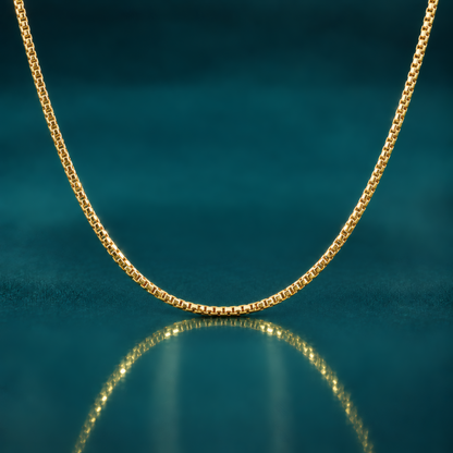 Classic 16" 1.5mm 14k yellow gold round box chain on a reflective teal surface.