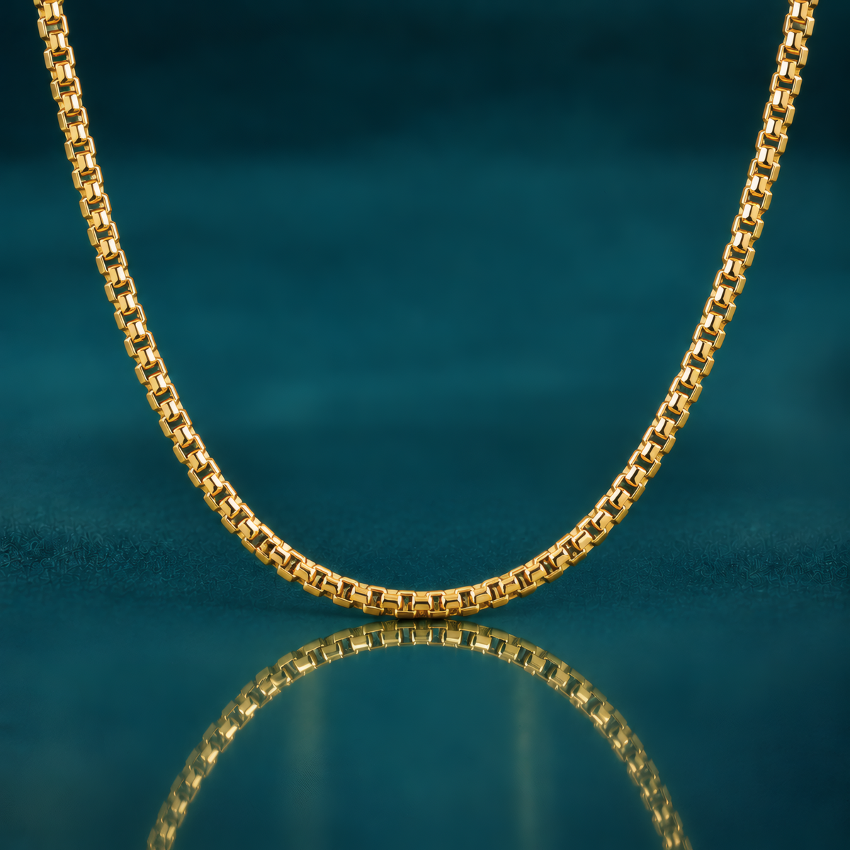 Bold 20" 3.6mm 14k yellow gold round box chain on a reflective teal surface.