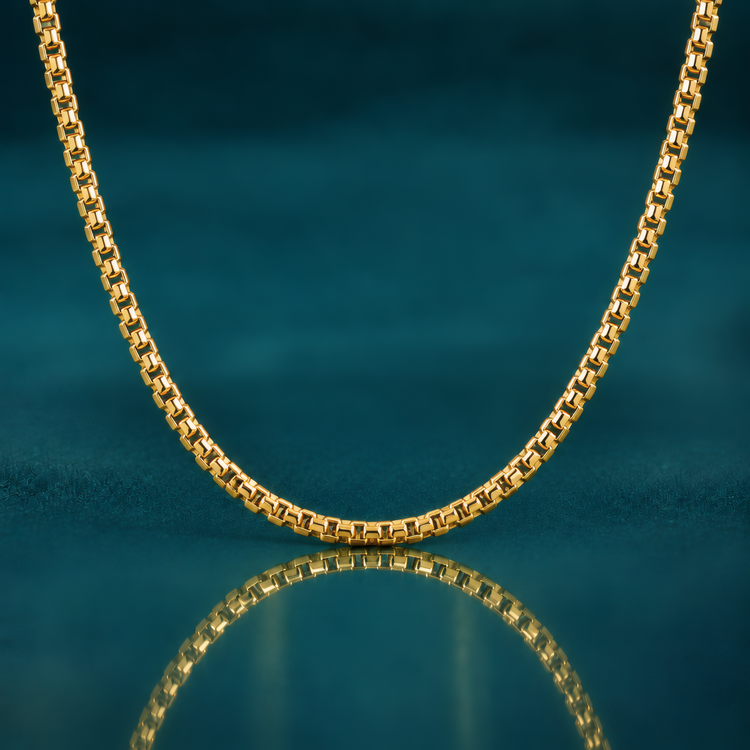 Bold 20" 3.6mm 14k yellow gold round box chain on a reflective teal surface.