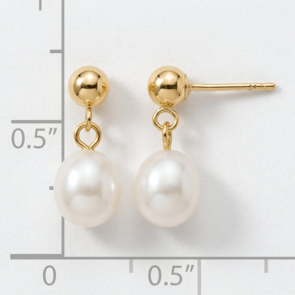 White freshwater pearl drop earrings on 14k yellow gold ball posts, on a white background with an inch scale.