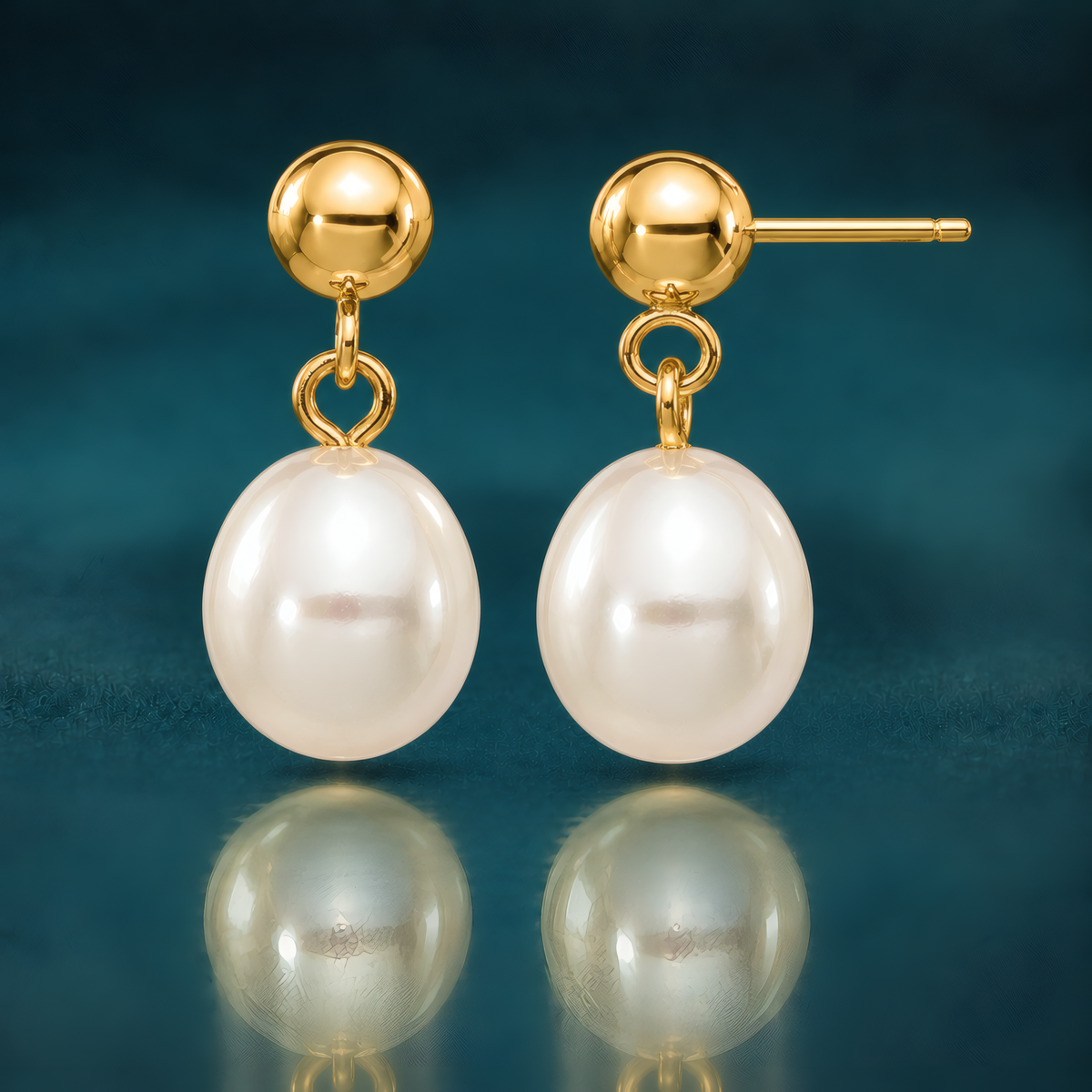 White rice-shaped freshwater cultured pearl drop earrings on 14k yellow gold ball posts, on a reflective teal surface.