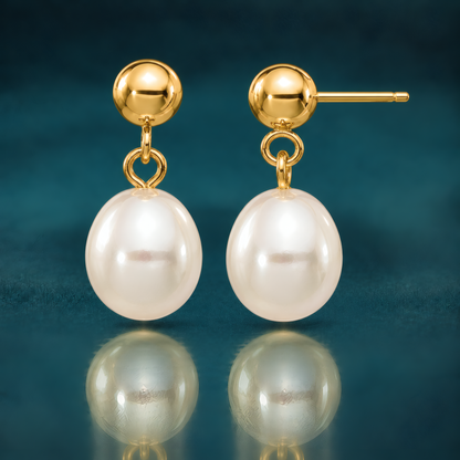 White rice-shaped freshwater cultured pearl drop earrings on 14k yellow gold ball posts, on a reflective teal surface.