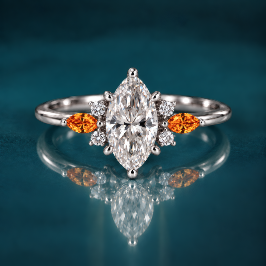 A white gold engagement ring with a striking marquise center diamond, flanked on each side by a fiery amber marquise accent and a cluster of sparkling round diamonds that catch the light like autumn sun. A slender, polished band keeps the look delicate and refined.