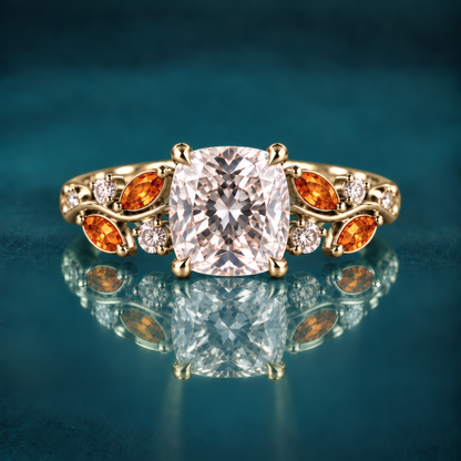 Gold engagement ring with a cushion-cut diamond atop a delicate vine band, woven with fiery amber marquise leaves and twinkling round diamonds for a romantic, nature-inspired look.