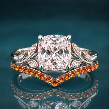 Ember is a white gold engagement ring with a cushion-shaped center diamond embraced by a vivid orange curved wedding band and sculpted leaf accents, all the warmth of fall in a single statement piece.