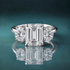 A white gold three-stone diamond ring featuring a central emerald-cut diamond flanked by two round-cut diamonds.