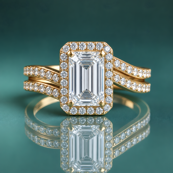 Gold halo engagement ring with an emerald-shaped center diamond and a curving double shank set with small diamonds.