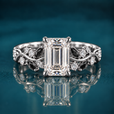Noctis pairs white gold with an emerald-cut diamond with a winding vine band set with deep black marquise accents and sparkling round diamonds, a striking contrast of light and shadow.