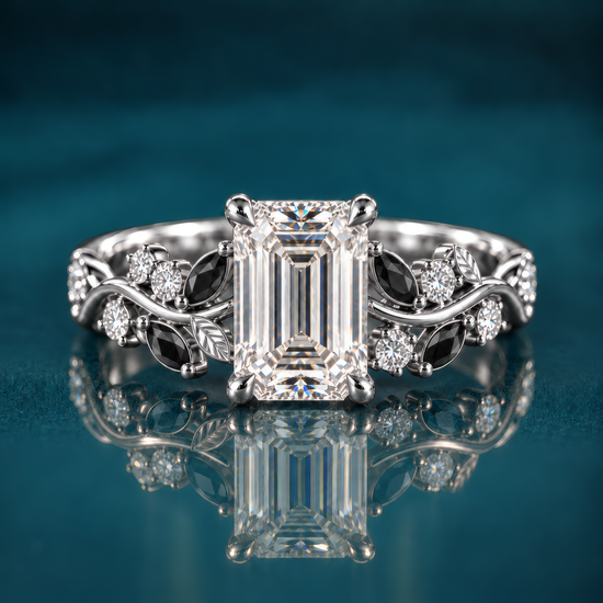 Noctis pairs white gold with an emerald-cut diamond with a winding vine band set with deep black marquise accents and sparkling round diamonds, a striking contrast of light and shadow.