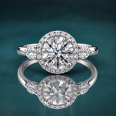 White gold halo three-stone engagement ring with a round center diamond and 2 pear-shaped side diamonds.