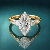Gold three-stone engagement ring with marquise center diamond and round side diamonds. Twist shank with accent small diamonds.