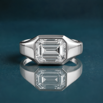 unique white gold solitaire engagement ring featuring a horizontal emerald-cut diamond and a thick band.