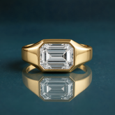 unique gold solitaire engagement ring featuring a horizontal emerald-cut diamond and a thick band.