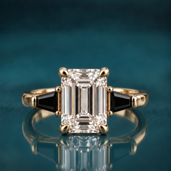 Tavi engagement ring in yellow gold featuring an emerald-cut diamond flanked by two tapered black baguettes