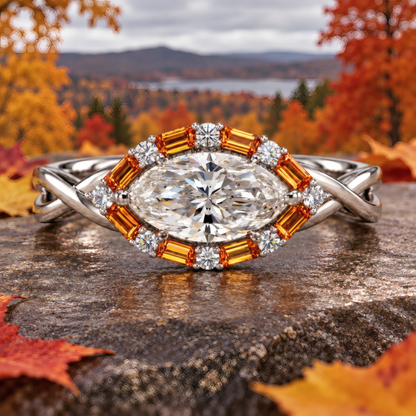 Vasa engagement ring in white gold with an east-west marquise diamond and amber baguette halo, resting on a stone with autumn trees and a lake behind